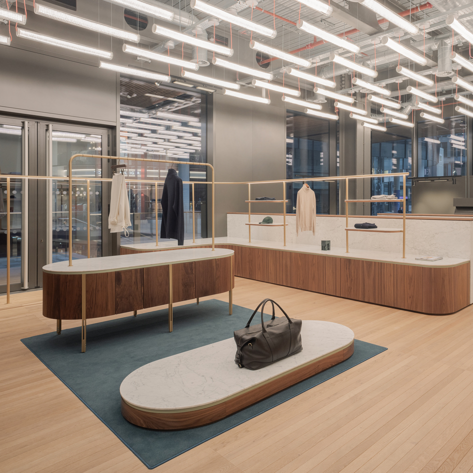Luca Faloni showroom with wood and marble furnishings, illuminated by rows of suspended Criosfera lamps.