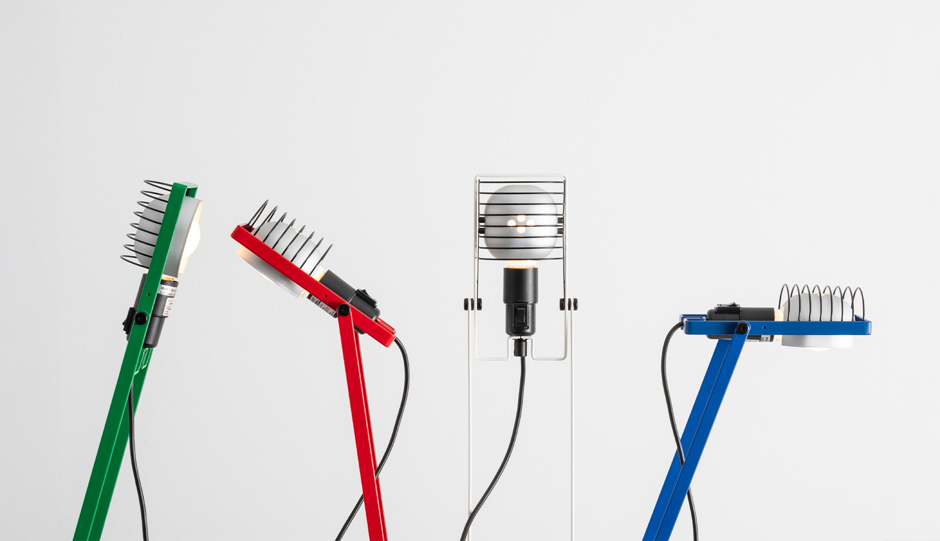 Close-up of four colored Sintesi lamps in different positions, on a white background.