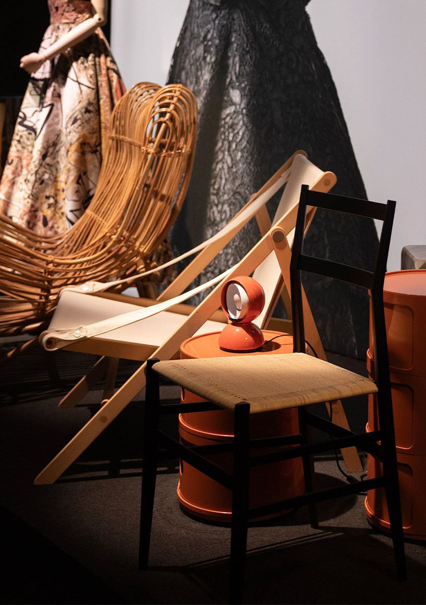Orange Artemide Eclisse lamp displayed on an orange side table, surrounded by seating and historic garments at the ABITO exhibition.