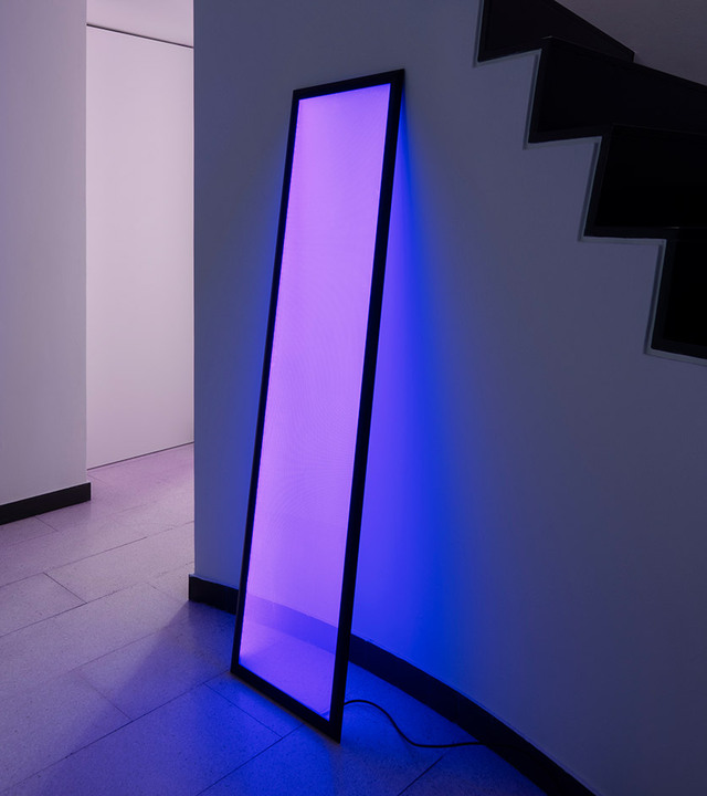 Vertical light panel with purple glow leaning against wall.