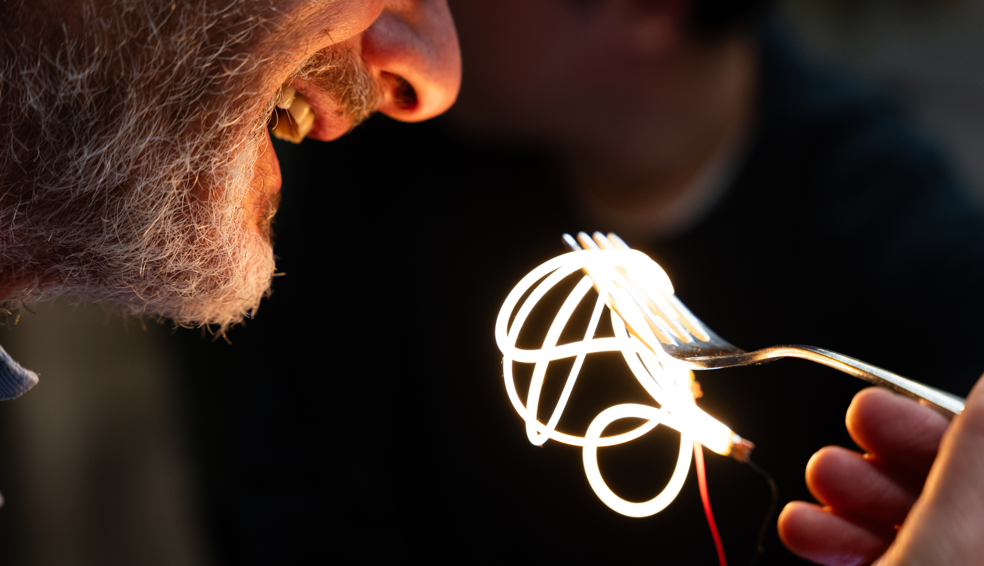Surreal image of a person eating luminous spaghetti.