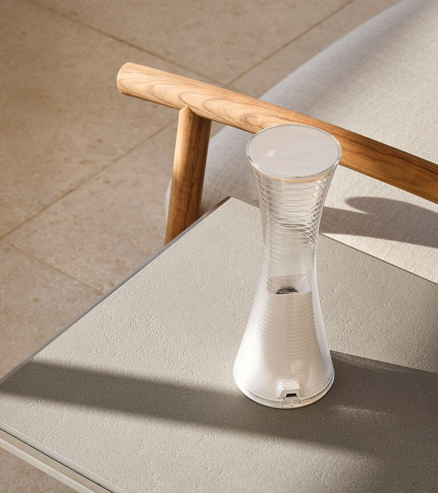 Artemide portable table lamp with hourglass-shaped ribbed white body and frosted top diffuser, placed on an outdoor side table