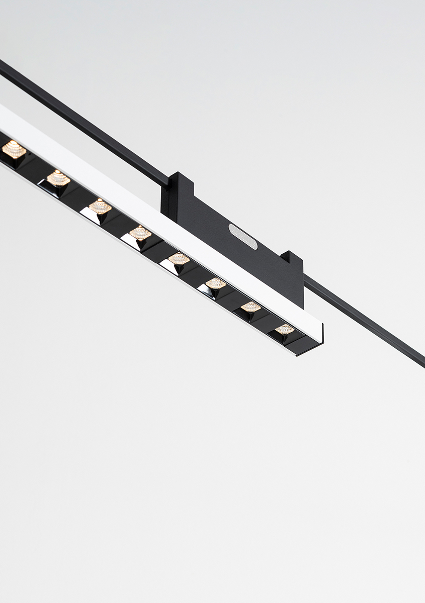 Black linear LED track light fixture with multiple adjustable spotlights mounted on a ceiling rail system