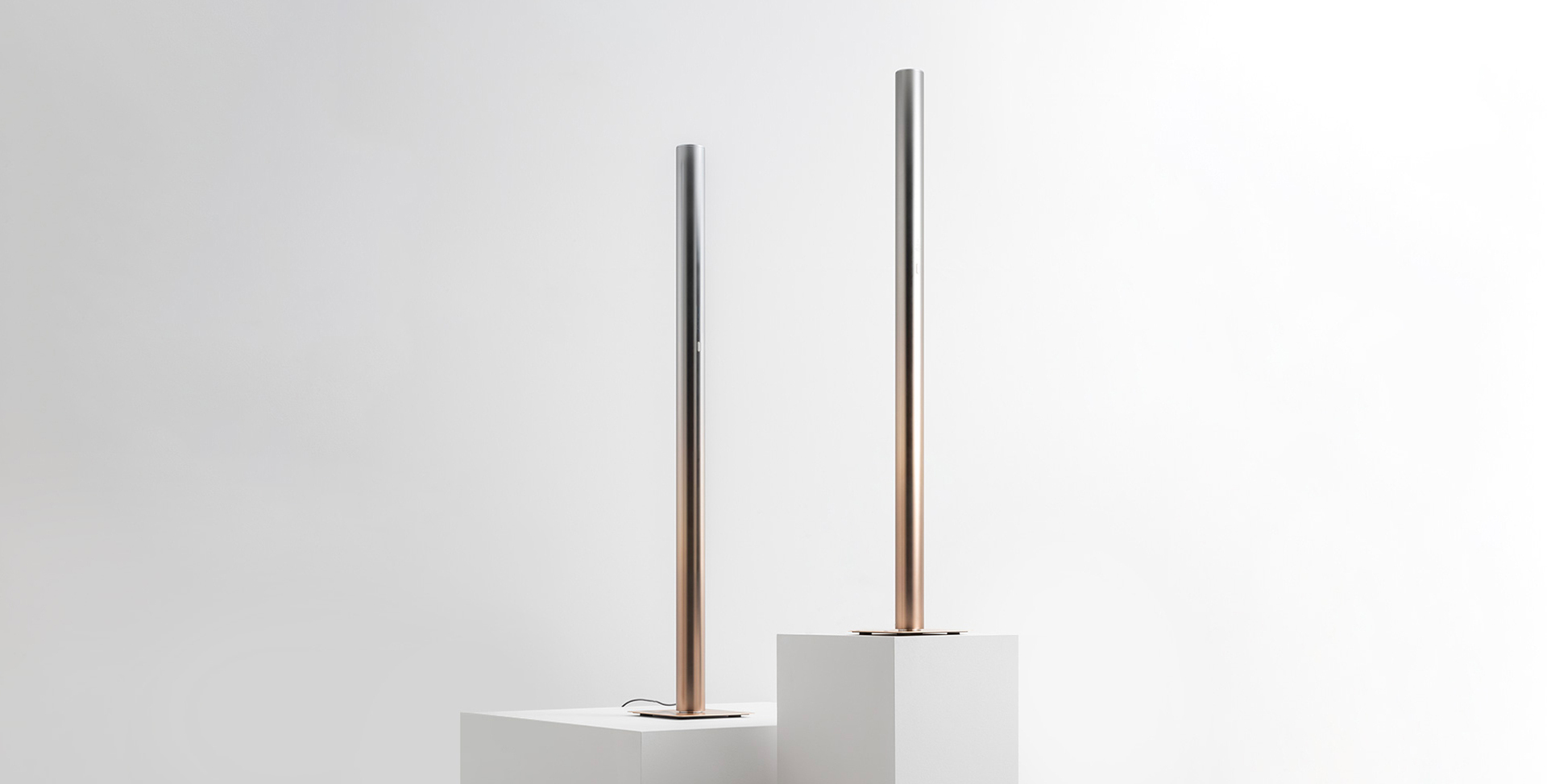 Image with two ilio lamps with a gradient coloring from silver to gold placed two white cubes.