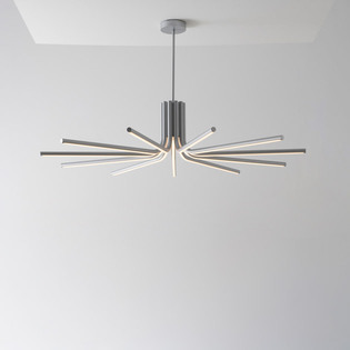 Veil pendant lamp with radiant linear arms, installed in a minimal interior with light-colored walls.
