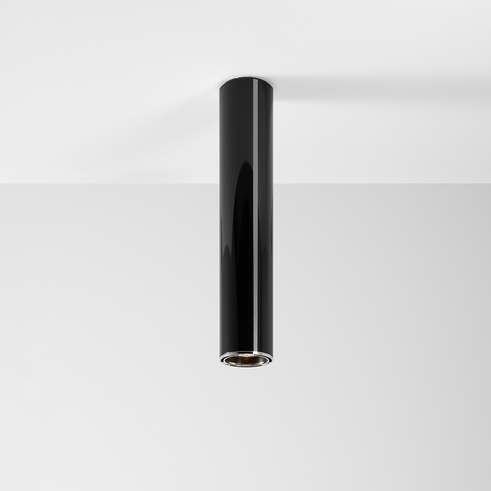Artemide Ilio ceiling spotlight: slim glossy black cylindrical tube with integrated LED, surface-mounted on white ceiling