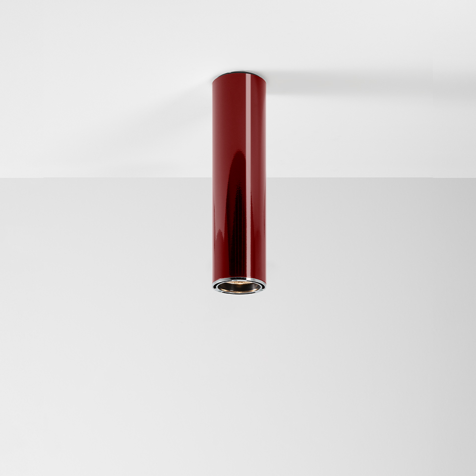 Artemide Ilio ceiling spotlight: glossy red cylindrical body flush-mounted on white ceiling, downward-facing LED aperture