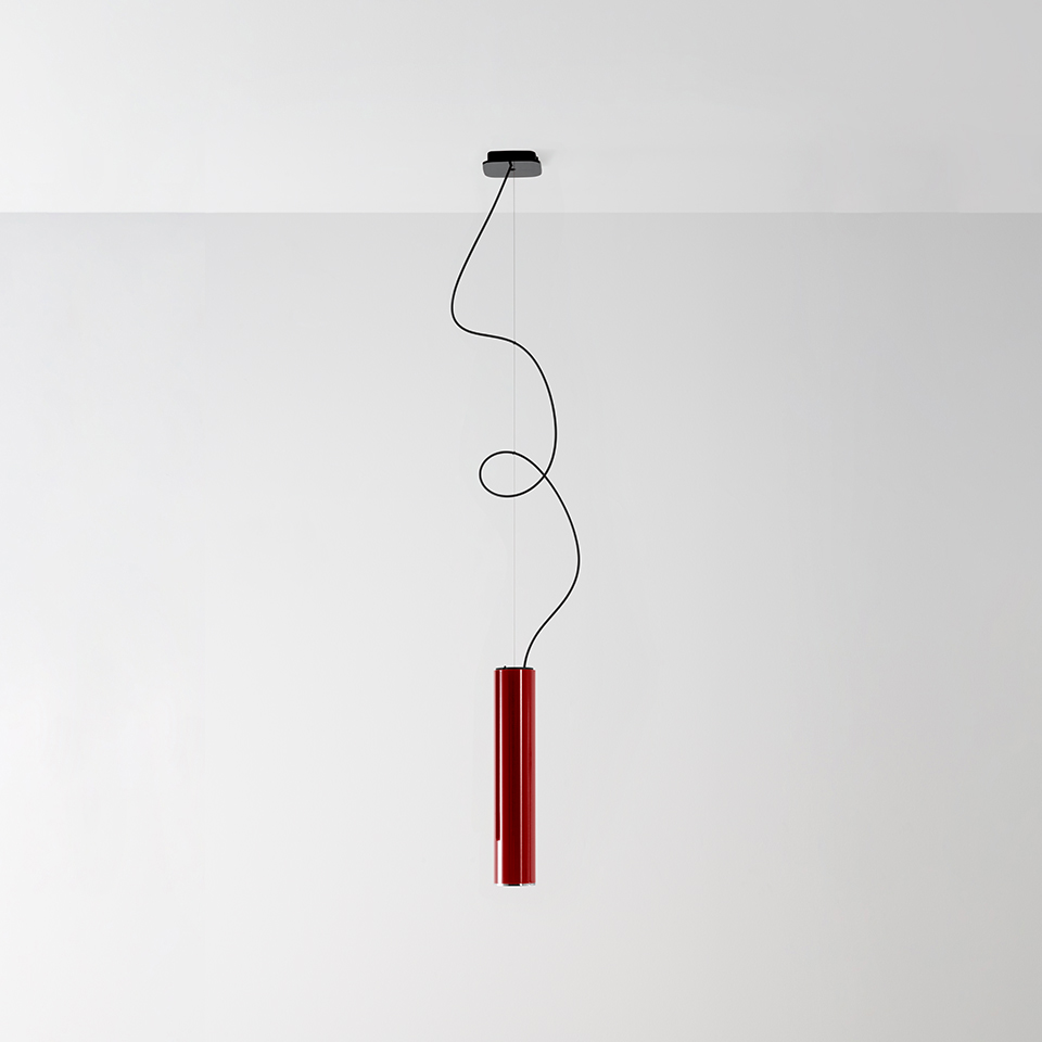 Artemide Ilio pendant lamp: slim red cylindrical body suspended by a looping black cable from a ceiling canopy