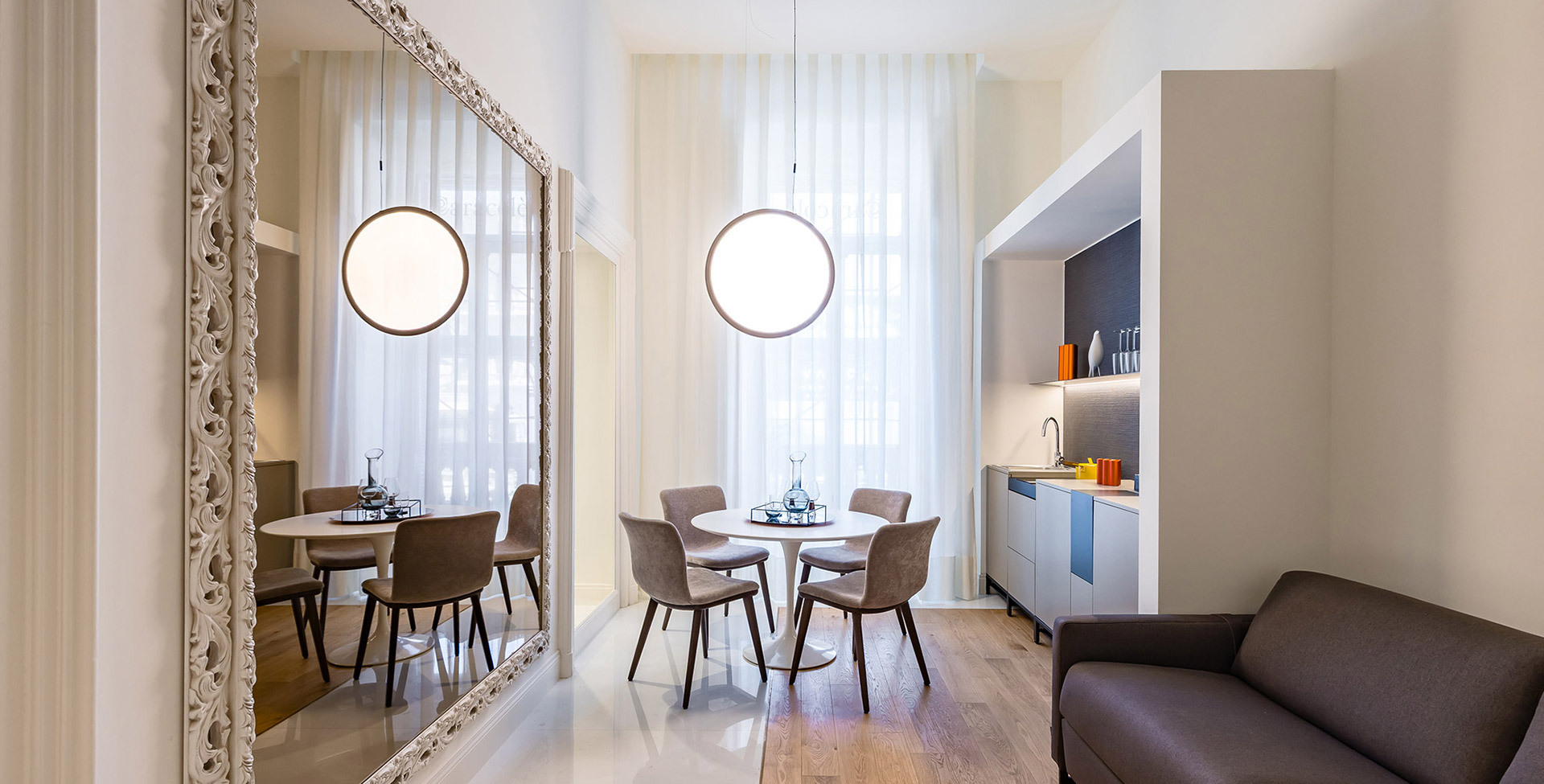 Open space with planters, lounge areas and circular lighting systems suspended in a timber structure.