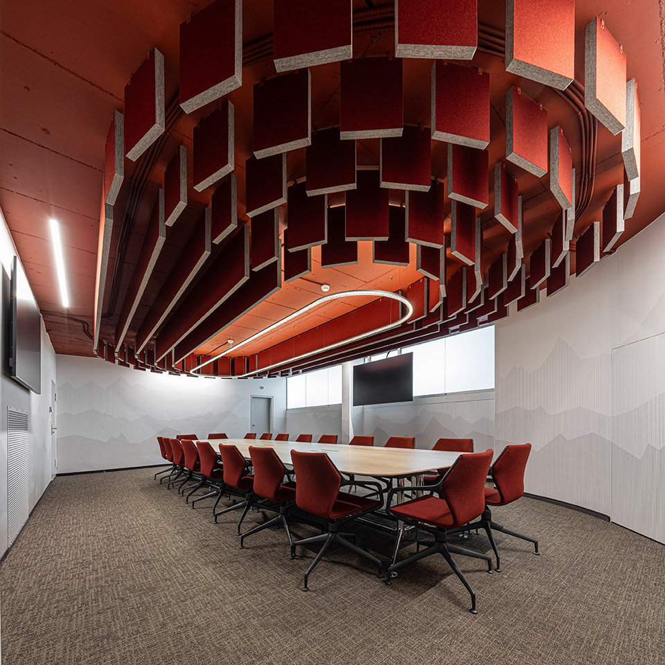 Suspended Somnĭum System light fixture above the table in a meeting room with acoustic ceiling panels.