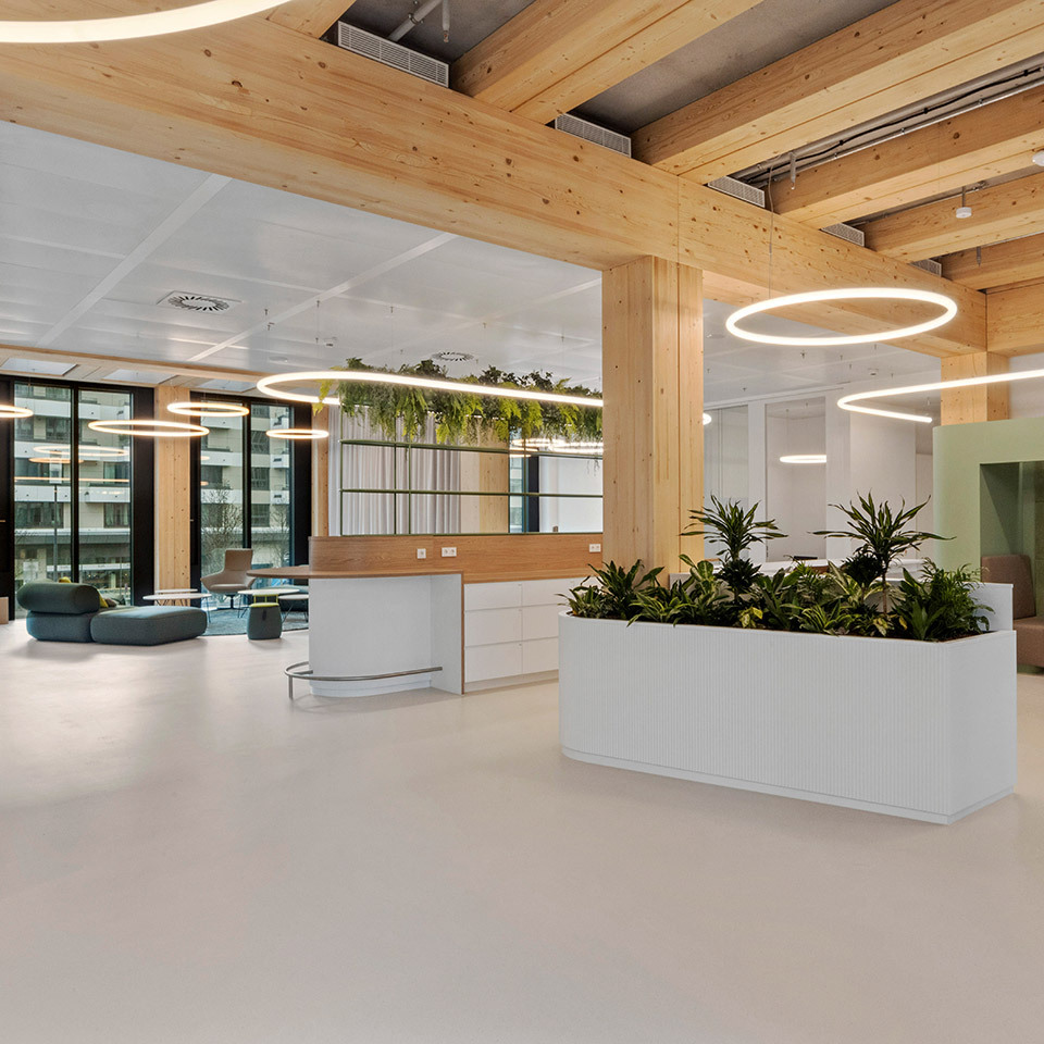 Open space with planters, lounge areas and circular lighting systems suspended in a timber structure.
