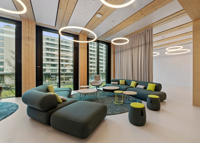 Bright lounge with modular sofas, large windows and circular pendant lights.