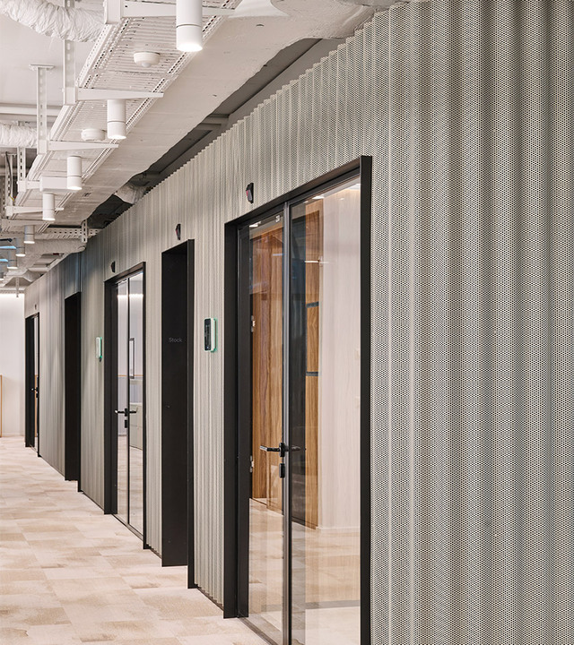 Modern hallway with perforated metal walls and black-framed glass doors.