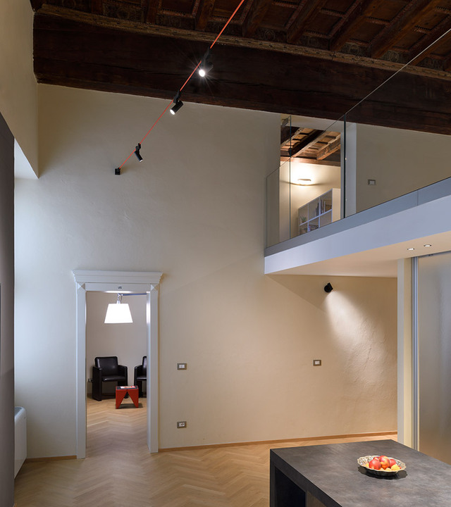 Funivia’s red cable and adjustable spotlights cross a historic double-height interior with a mezzanine.