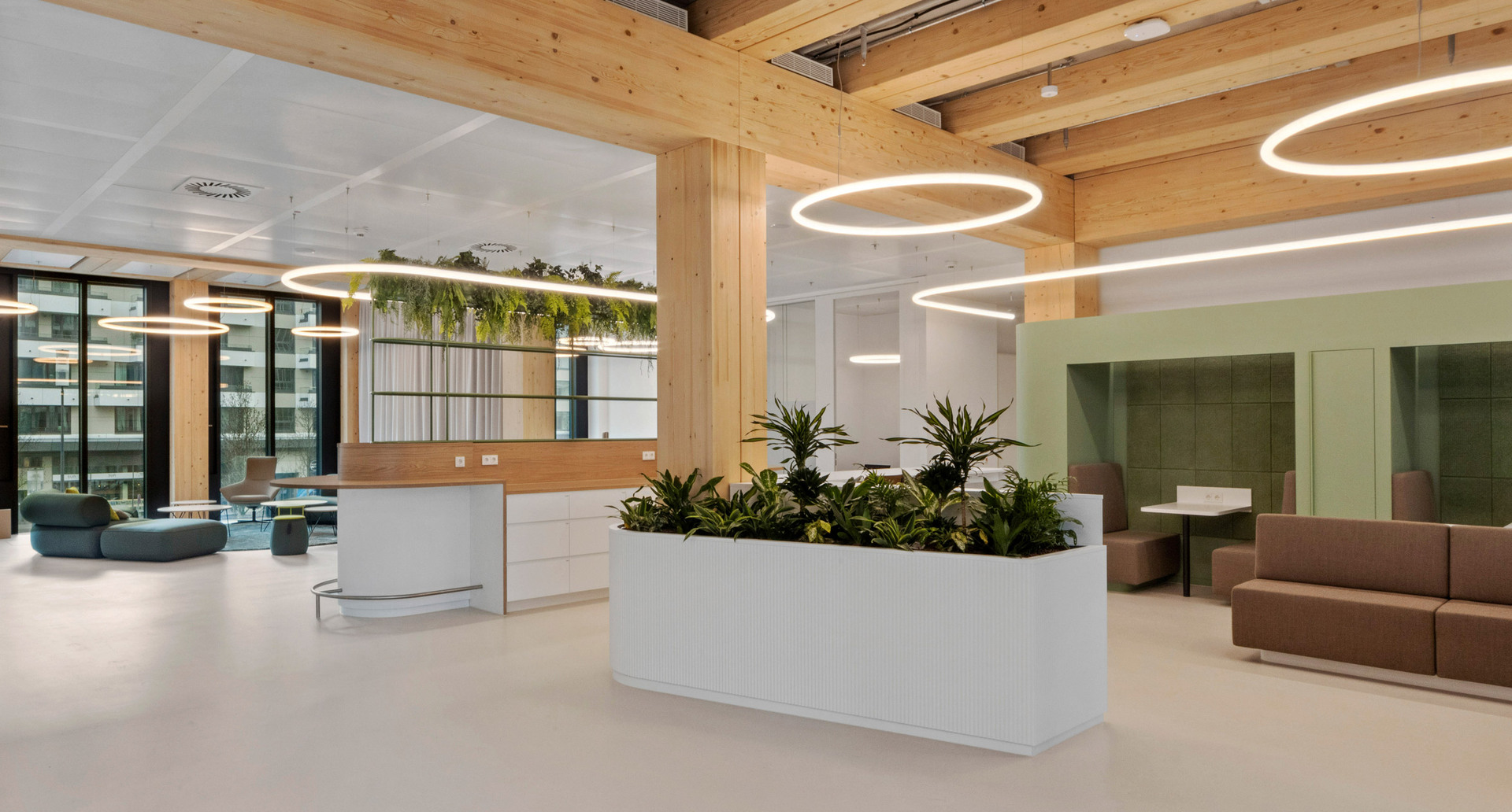 Open space with planters, lounge areas and circular lighting systems suspended in a timber structure.