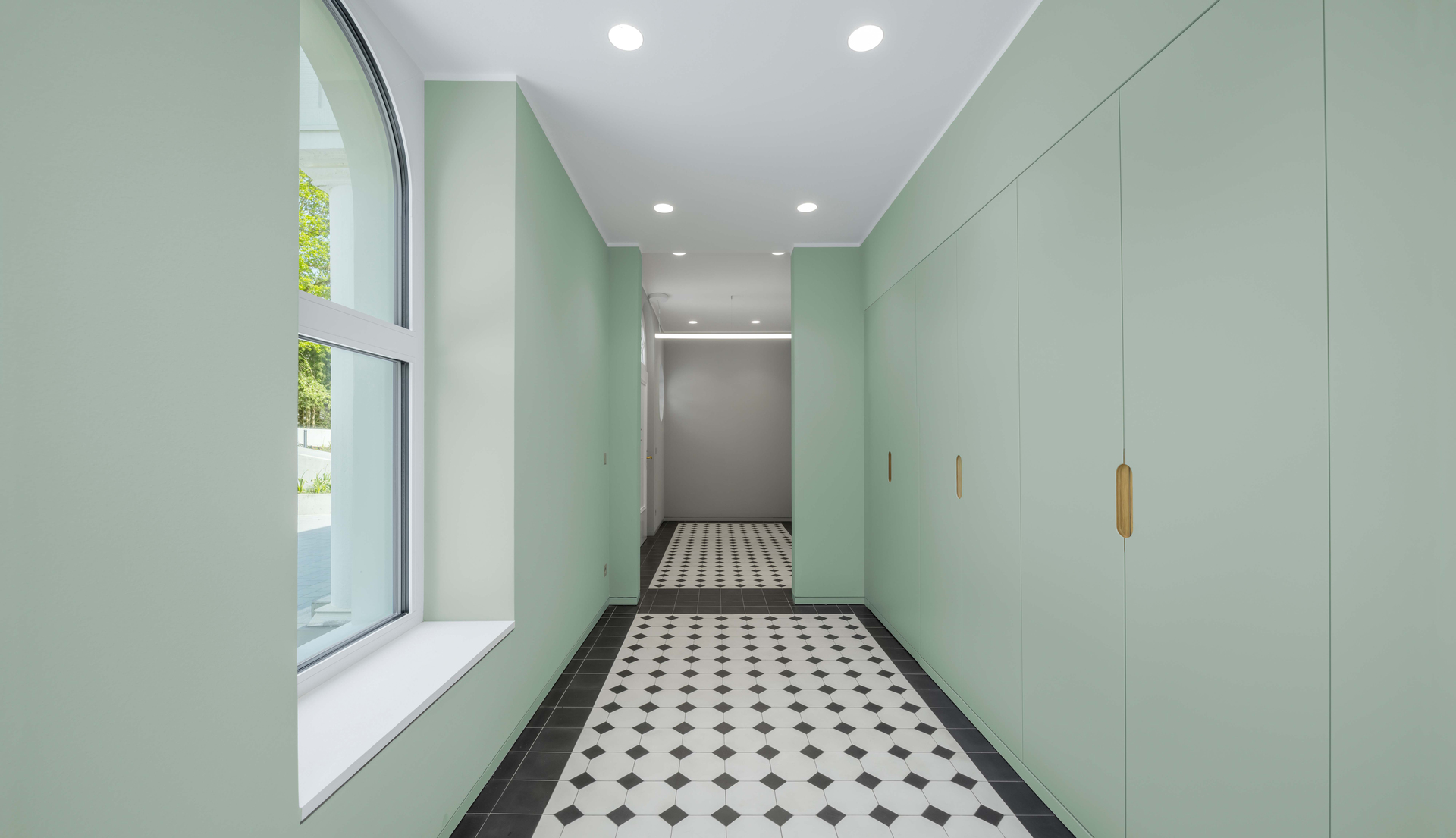 Image of a corridor with sage green walls and a black and white geometric floor, lit by Everything.