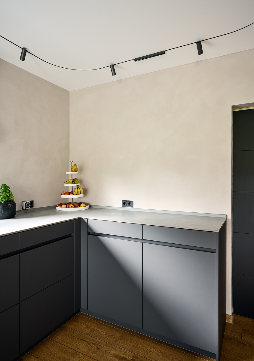 Kitchen corner with gray base units, beige wall, light worktop, and the curved Turn Around system on the ceiling.