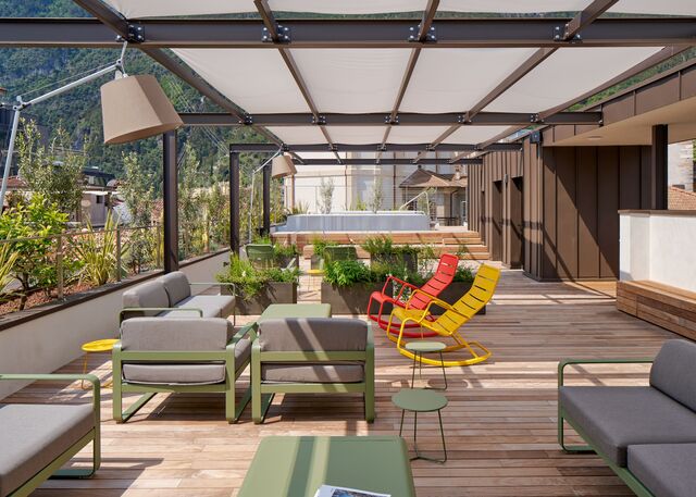 Image of the hotel exterior with benches and tables illuminated by Tolomeo Paralume Outdoor.