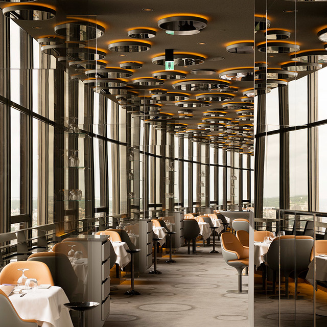 Elegant restaurant ceiling with rows of circular pendant lights with gold accents, reflecting on mirrored columns above dining tables.