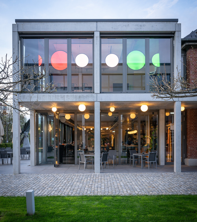 Image of the outside of the event space, the veranda illuminated by Dioscuri Ceiling and inside you can see a series of Discovery Verticals.