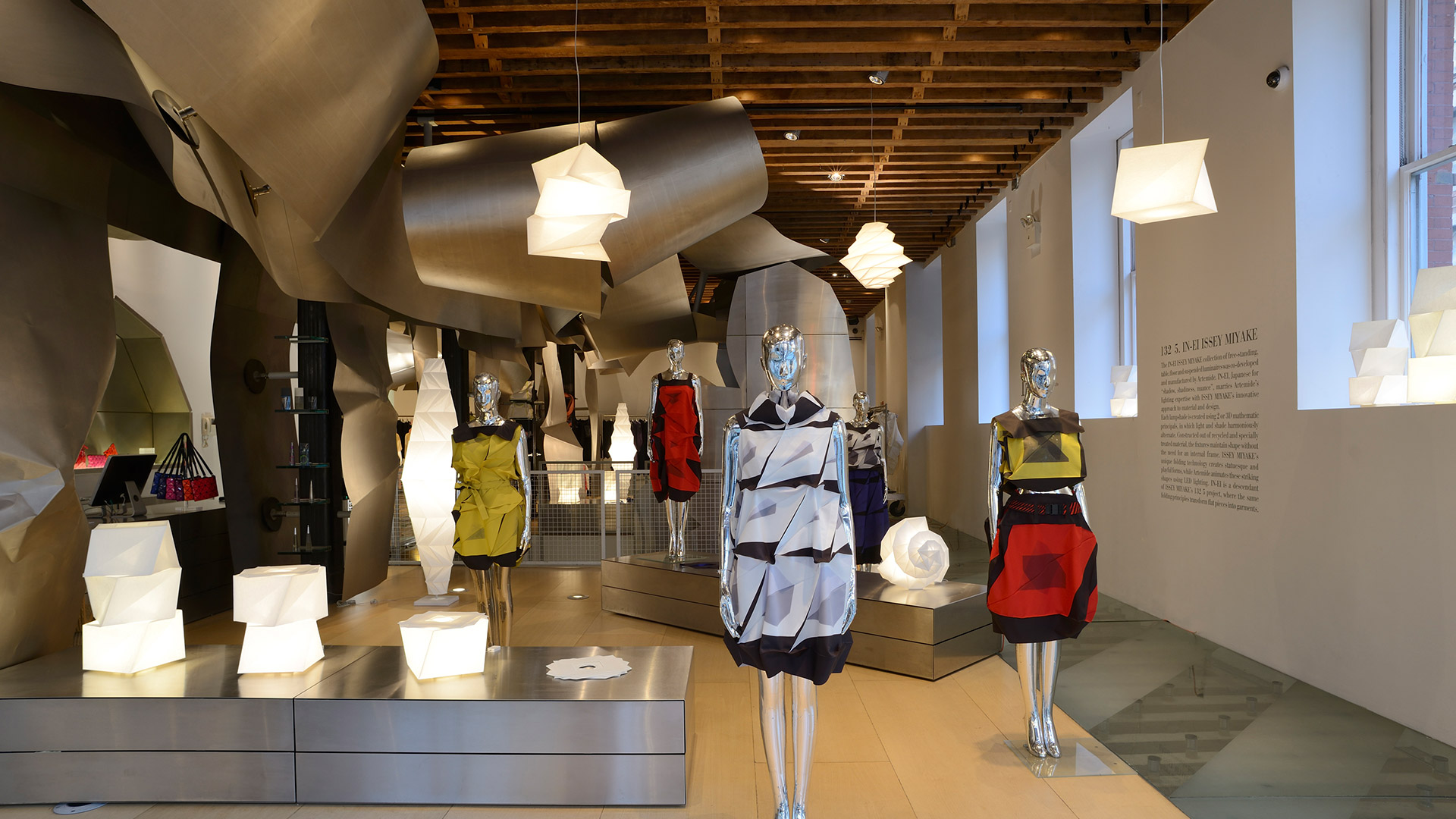 Artemide In-Ei Issey Miyake Minomushi: three origami-folded white pendant and floor lamps glowing against a dark background