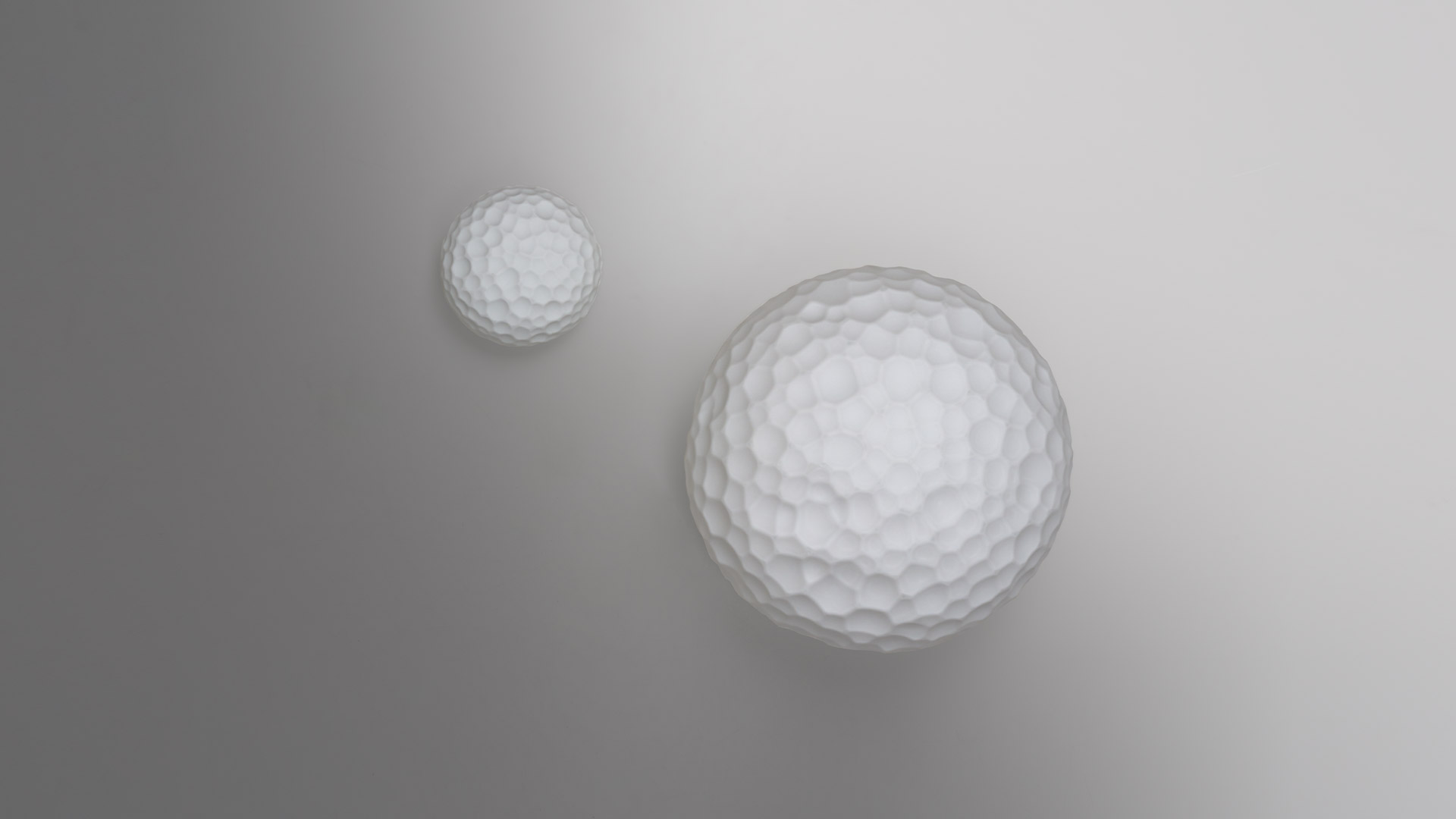 Two Artemide Meteorite lamps with textured spherical diffusers: one small wall-mounted and one larger ceiling version on grey background